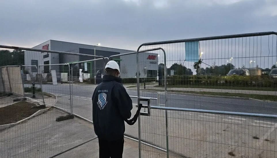 MW Global Security Services, Security guard unlocking an heras fence gate at construction site.