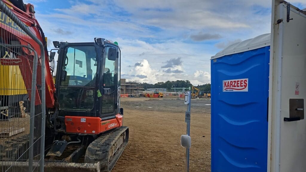 Temporary Ajax alarm system protecting site cabin on active construction site in Cambridgeshire with plant machinery and groundworks in progress.