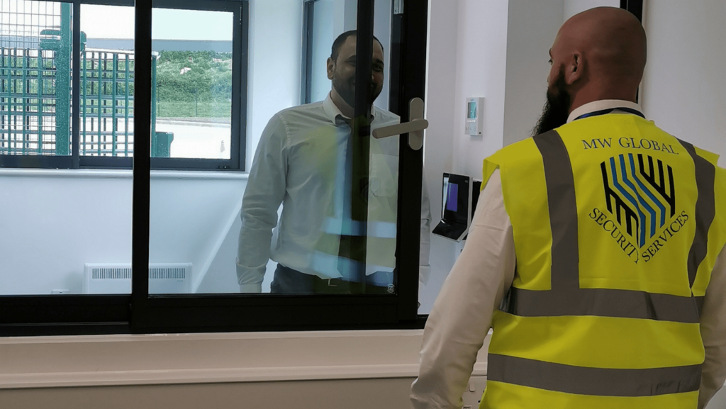 Gatehouse security officer assisting a visitor at a secure check-in point